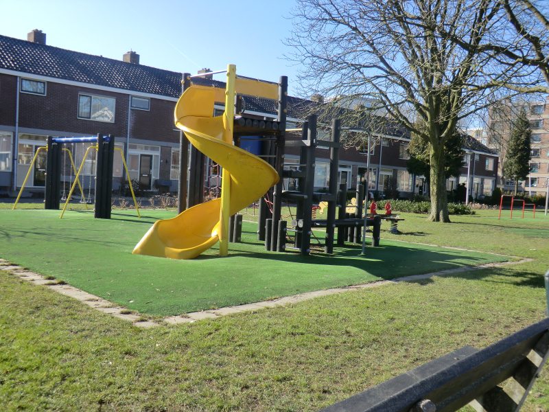 De speeltuin met gele glijbaan in de straat