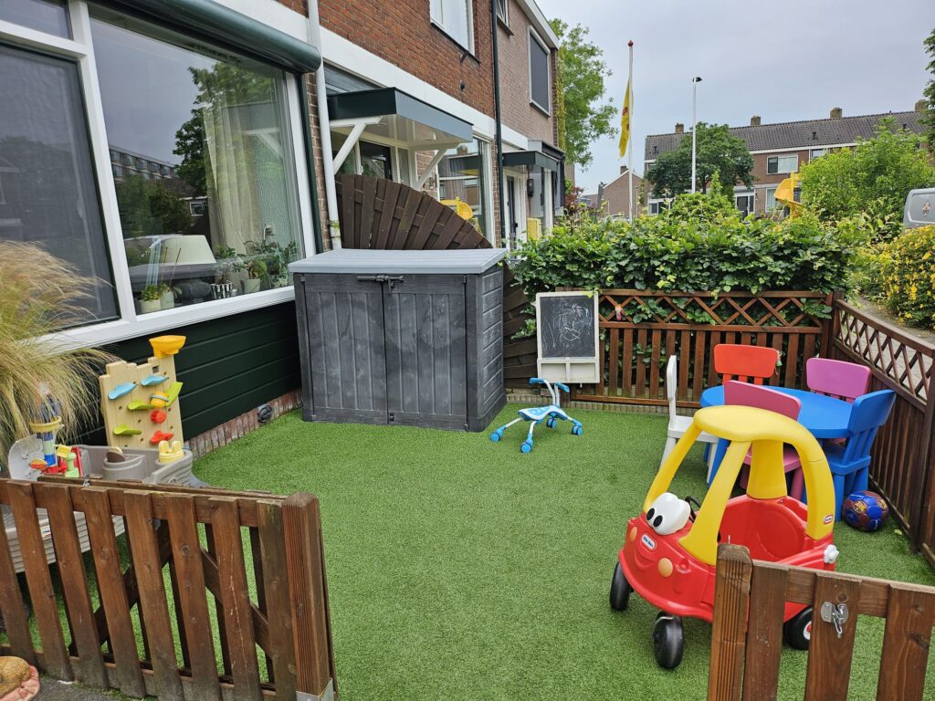De afgesloten voortuin met speeltoestellen van de opvang